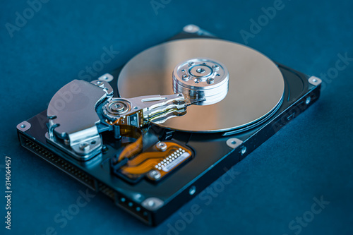 Hard disk drive platter.Disassembled hard drive from the computer with mirror effect. HDD. Detail of writing/reading head on actuator arm and axis, spindle and platters.