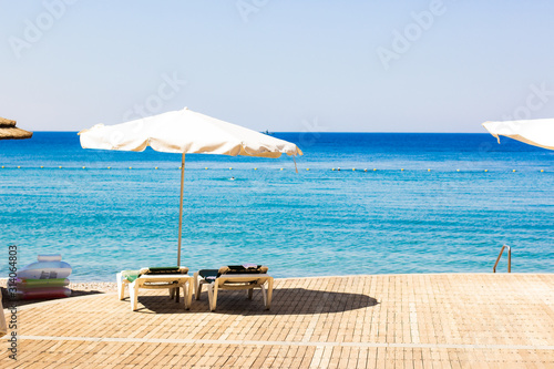 summer time resort hotel beach coast line scenic landscape view of umbrella lounge furniture deck chair on wooden deck floor and Red sea blue water horizon backgroundcopy copy space photo