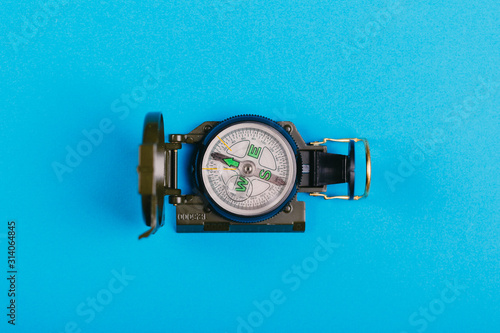 metal navigation travel compass on a blue background. search for a way. point of view