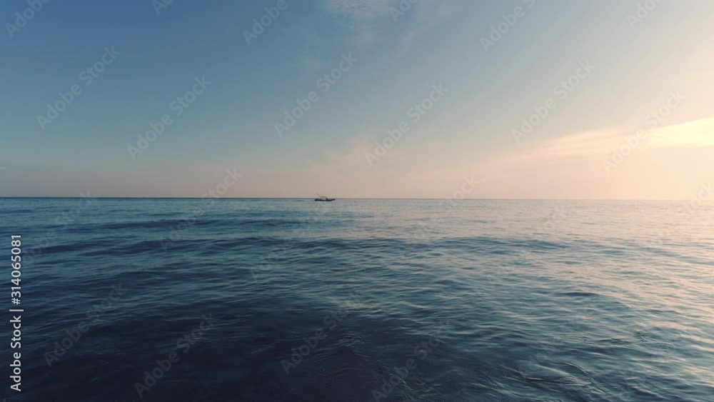 Sailing fishing boat in the sea water early in the morning and beautiful sunrise