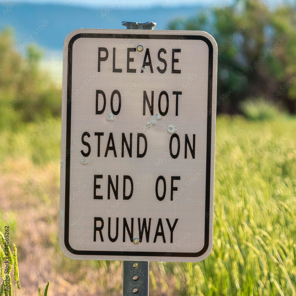 Square frame Road sign with grasses trees mountain and cloudy sky in the blurry background