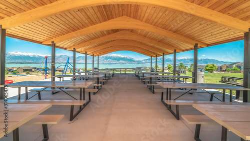 Pano Pavilion with brown wooden ceiling overlooking lake and snow capped mountain © Jason