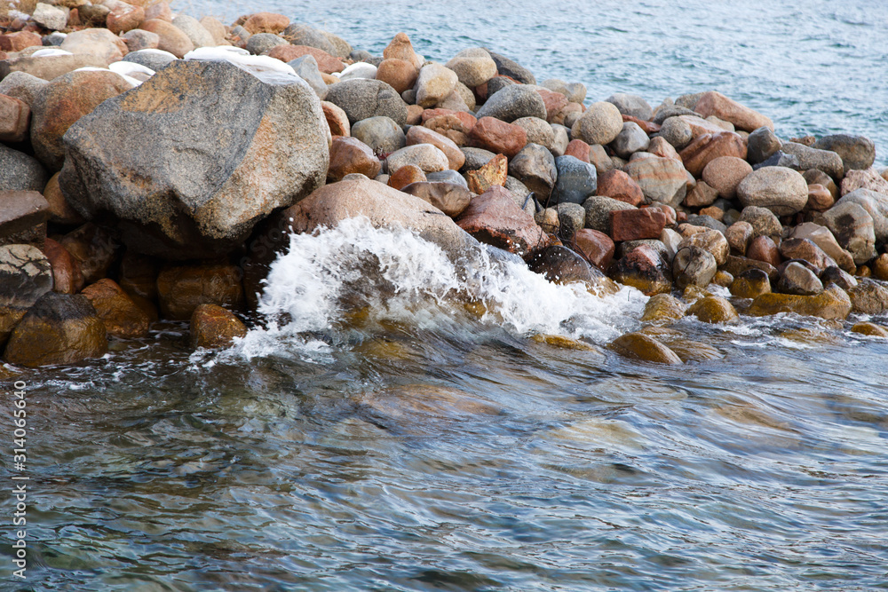 Stones on the sea beach. Pasture winter day. Clear water and sand. Kyrgyzstan, Issyk-Kul Lake Stones on the sea beach. Pasture winter day. Clear water and sand. Kyrgyzstan, Issyk-Kul Lake