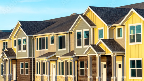 Pano frame Exterior view of townhomes with gable roof stairs and square columns at entrance