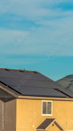 Vertical frame Solar panels on gable roof of home against mountain and blue sky background