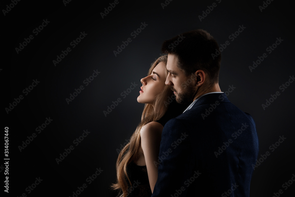 elegant couple on black background. man embracing beautiful woman in black dress. copy space elegant couple on black background. man embracing beautiful woman in black dress. copy space
