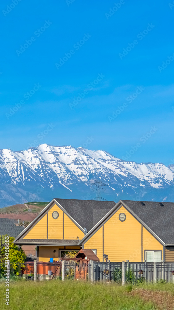 Vertical frame Single storey houses against striking snow capped mountain and vibrant blue sky