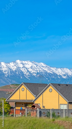 Vertical frame Single storey houses against striking snow capped mountain and vibrant blue sky © Jason