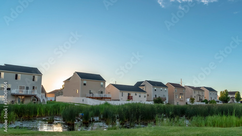 Pano frame Sunset in the suburbs with multi storey homes ovelookinga park with shiny pond