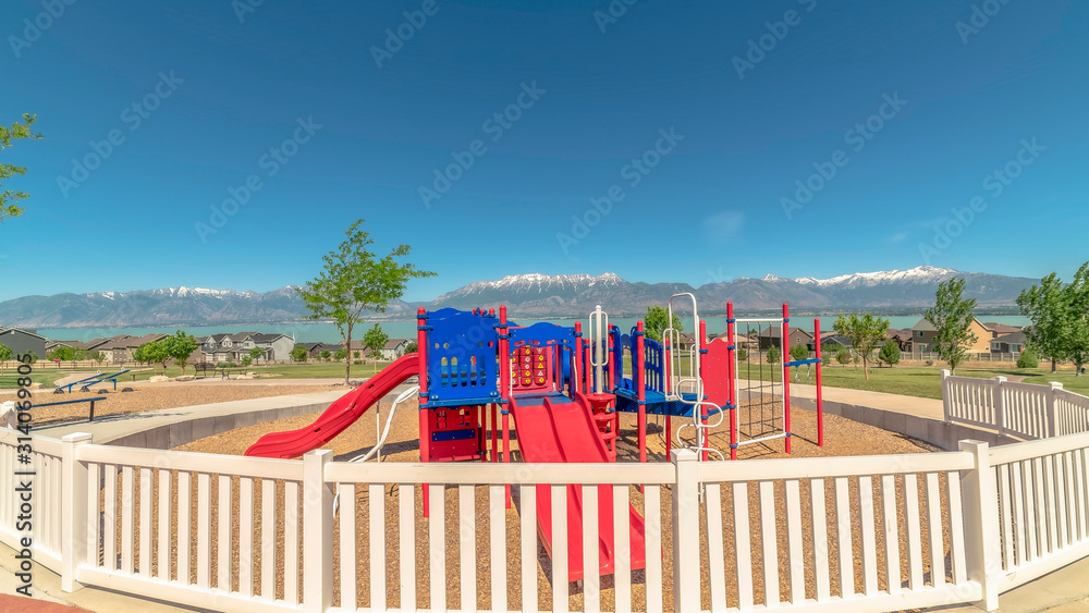 Pano frame Fun colorful childrens playground overlooking lake snowy mountain and blue sky Pano frame Fun colorful childrens playground overlooking lake snowy mountain and blue sky