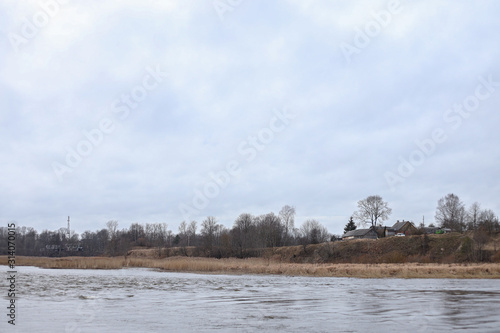 Riverside view of river flowing near countryside city with trees on winter.