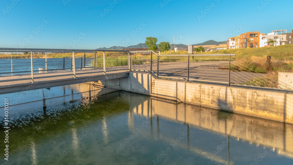 Pano Bridge over lake with lakefront buildings and mountain view under blue sky