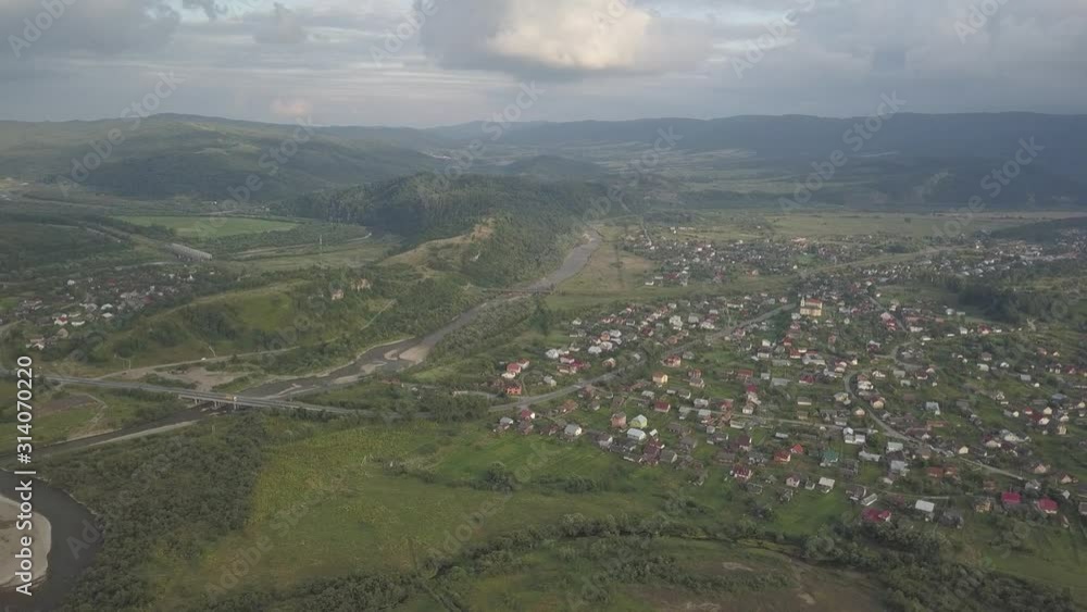 Morning in Transcarpathia. Aerial drone shooting from a bird’s flight of a mountain river with bridges and buildings in the summer. Beautiful nature of Europe. Panorama of the agricultural region. Morning in Transcarpathia. Aerial drone shooting from a bird’s flight of a mountain river with bridges and buildings in the summer. Beautiful nature of Europe. Panorama of the agricultural region.