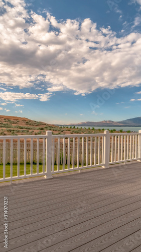 Vertical Back porch of a home with view of lake and mountain under cloudy blue sky