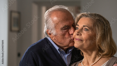 Close up of a lovely senior husband is giving a kiss to his wife as a sign of forever love at home.