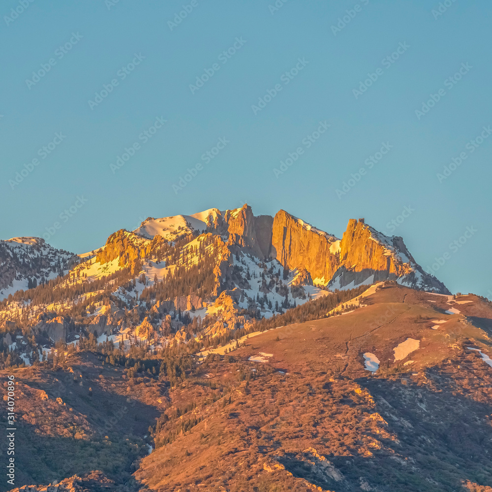 Square frame Striking mountain peak with rugged slopes against blue sky on a sunny day