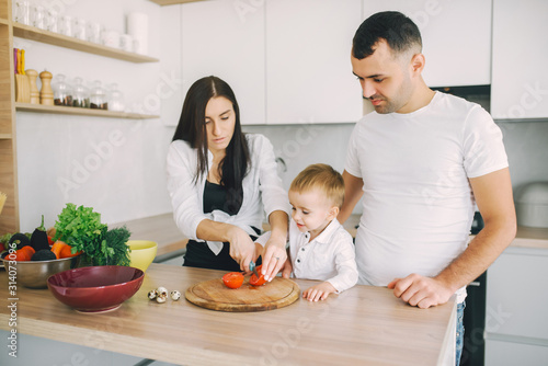 Family in a kitchen. Beautiful mother with little son. Father in a white t-shirt.
