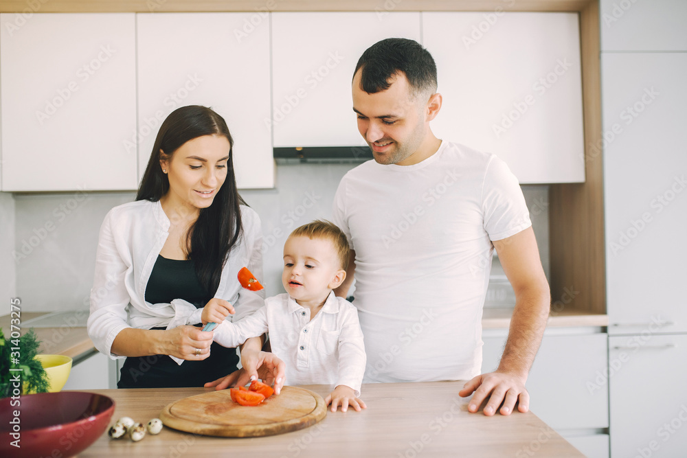 Family in a kitchen. Beautiful mother with little son. Father in a white t-shirt. Family in a kitchen. Beautiful mother with little son. Father in a white t-shirt.