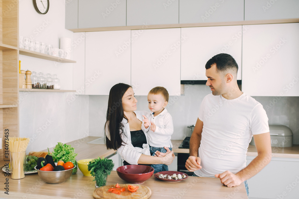 Family in a kitchen. Beautiful mother with little son. Father in a white t-shirt. Family in a kitchen. Beautiful mother with little son. Father in a white t-shirt.