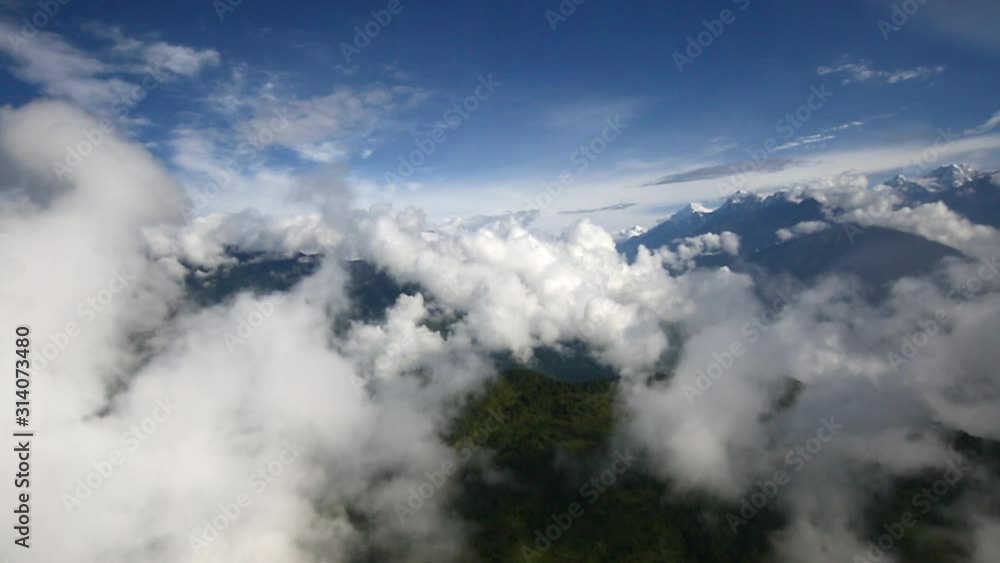 Flight over green overgrown mountain ridge with helicopter in Nepal. Flying through clouds over back of a mountain towards a deep green Nepalese valley in the highlands. Flight over green overgrown mountain ridge with helicopter in Nepal. Flying through clouds over back of a mountain towards a deep green Nepalese valley in the highlands.
