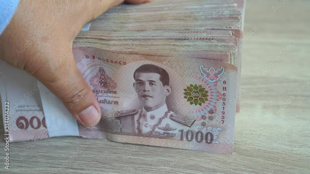 Stack Thai baht banknotes, Businessman's hands counting money. one thousand baht with tag text in Thai word. (THB) is official currency of Thailand. Finance and banking business in Asia concept