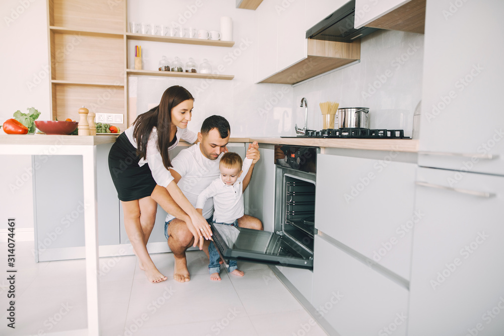 Cute little son in a white sweater. Family at home in a kitchen. Pregnant woman. Cute little son in a white sweater. Family at home in a kitchen. Pregnant woman.