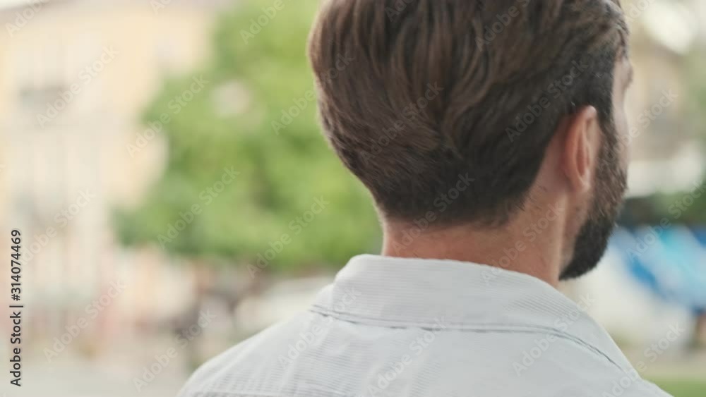 Back view young handsome man is walking by street outdoors in summer with pretty woman Back view young handsome man is walking by street outdoors in summer with pretty woman