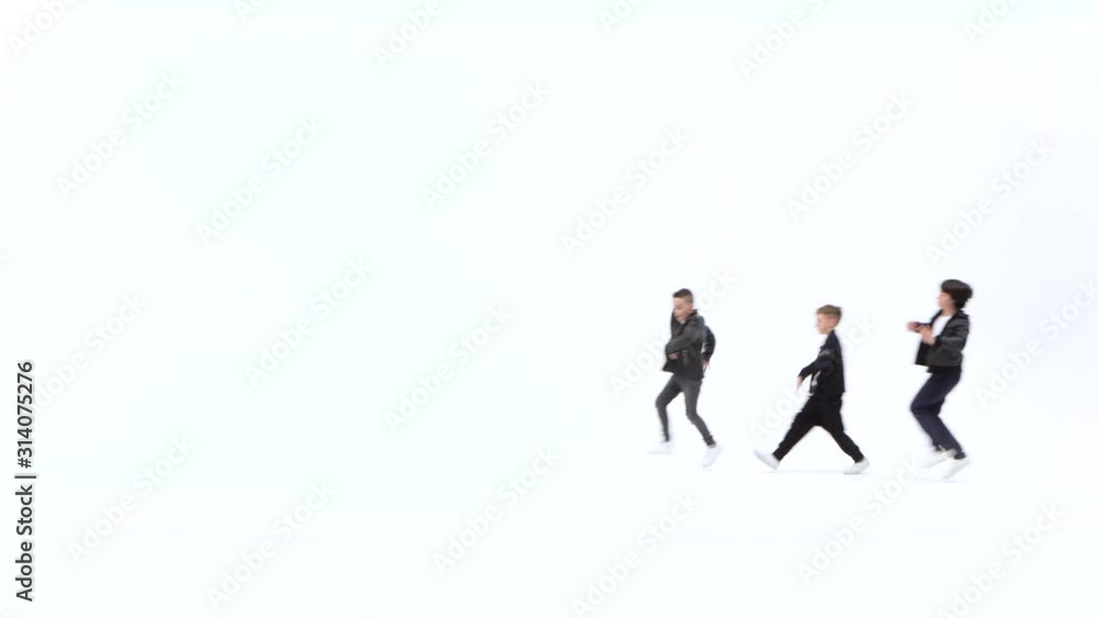 Little boys are dancing a modern dance on the white background in black leather jackets and jeans Little boys are dancing a modern dance on the white background in black leather jackets and jeans