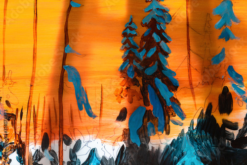 Picture of the winter forest at sunset in orange and blue tones is on a wooden easel in studio. Christmas and New Year concept, arts. photo