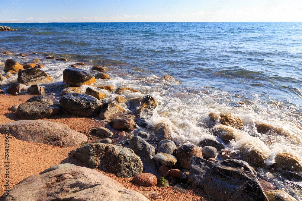 Stones on the sea beach. Pasture winter day. Clear water and sand. Kyrgyzstan, Issyk-Kul Lake