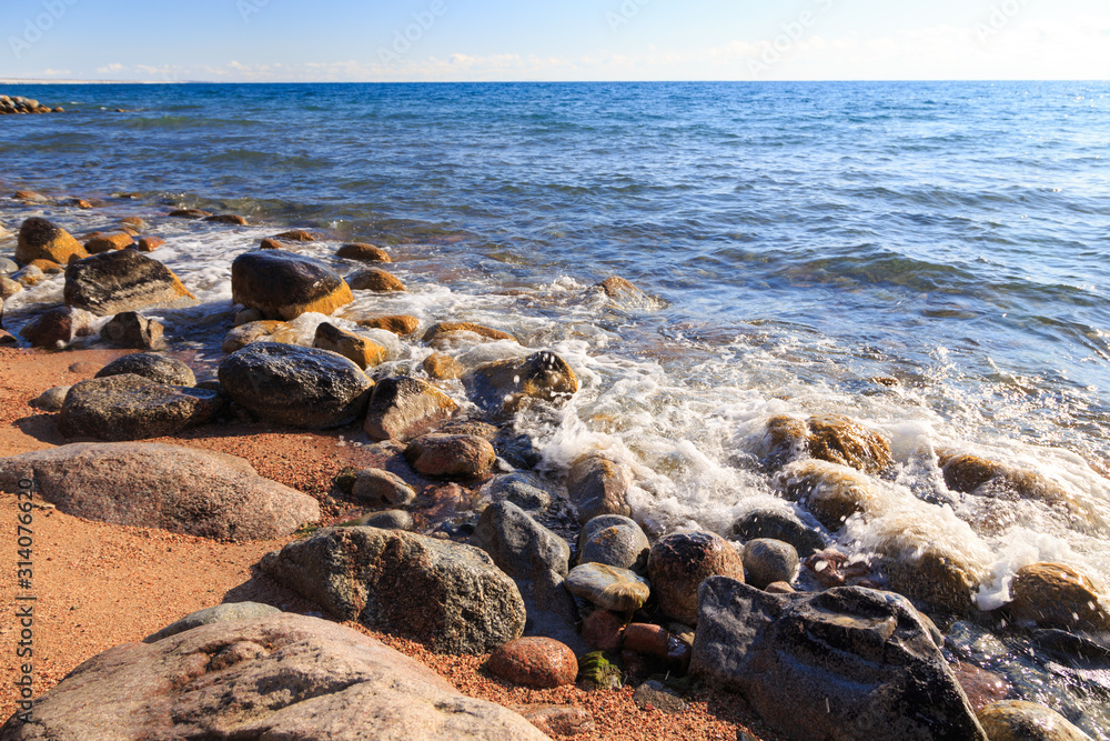 Stones on the sea beach. Pasture winter day. Clear water and sand. Kyrgyzstan, Issyk-Kul Lake Stones on the sea beach. Pasture winter day. Clear water and sand. Kyrgyzstan, Issyk-Kul Lake