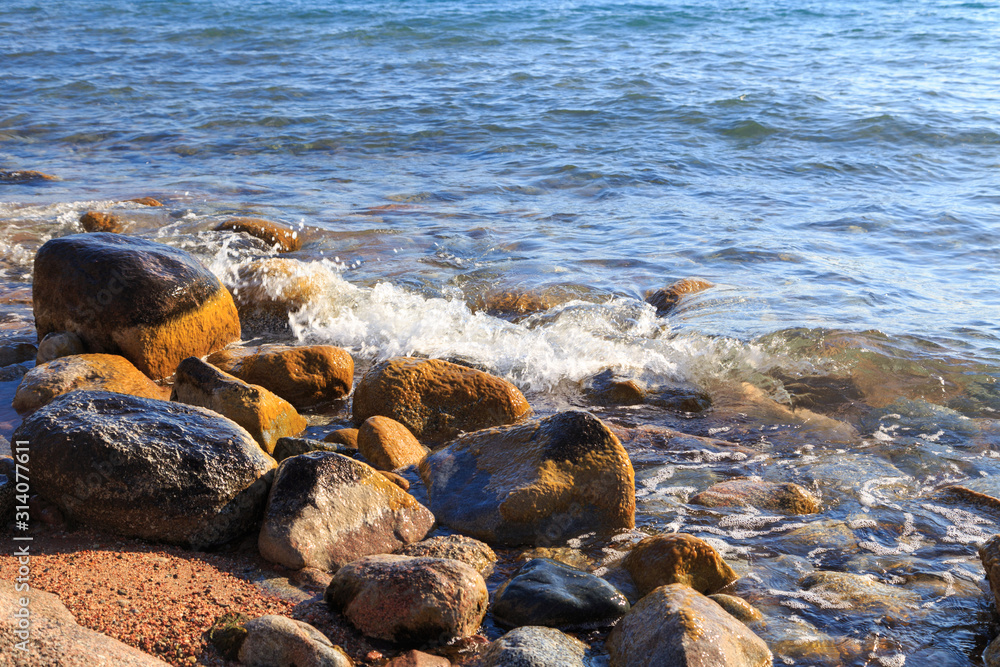 Stones on the sea beach. Pasture winter day. Clear water and sand. Kyrgyzstan, Issyk-Kul Lake Stones on the sea beach. Pasture winter day. Clear water and sand. Kyrgyzstan, Issyk-Kul Lake