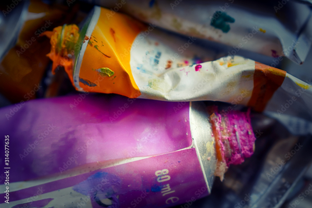 tubes of paint open and extruded orange and violet th color, blurred background
