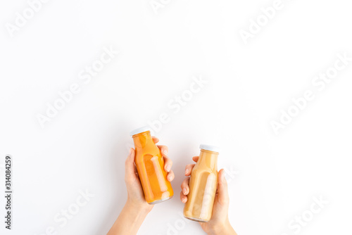 Bild auf Leinwand Female hands holding bottles of fruit and vegetable smoothies isolated on white background with copyspace