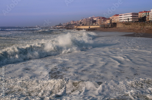 Powerful waves at the local beach. Residential buildings in the background photo