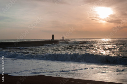 Sunset over the ocean, lighthouse on the background . Lighthouse as a Landmark photo