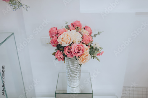 Closeup wedding bouquet of colorful roses stands in a glass vase. Wedding flowers, decorations, details, accessories. Photography, concept.