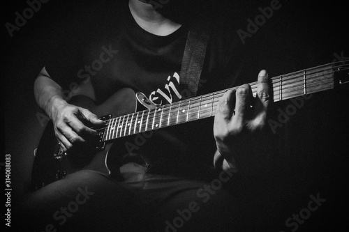 Close up view of man's hands playing electric guitar. Black and white picture