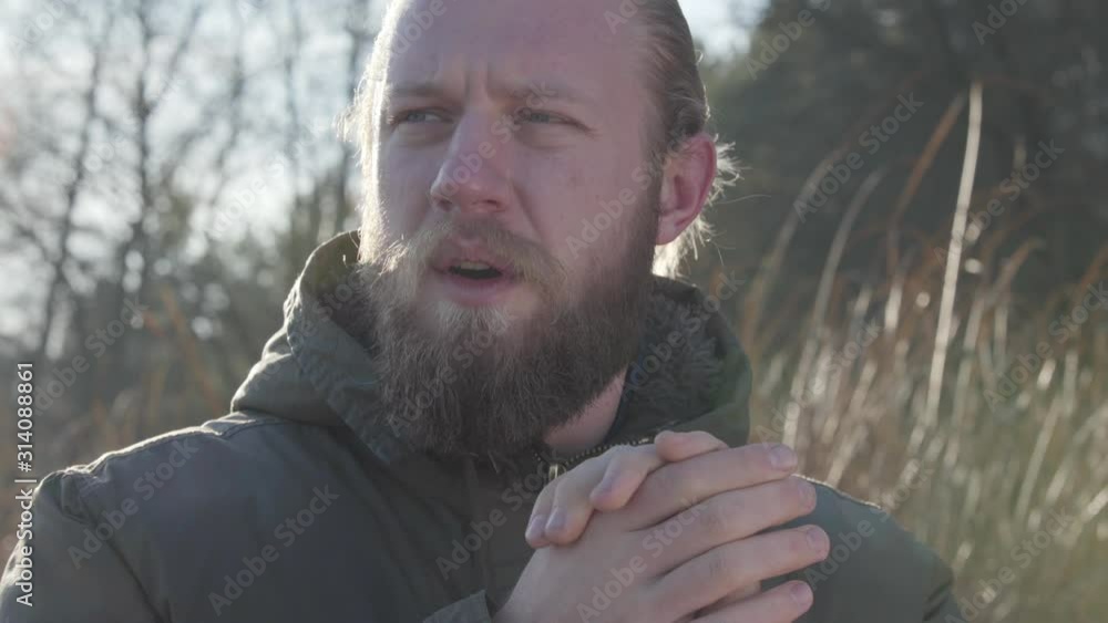 Close-up face of adult Caucasian male tourist standing in sunlight and blowing on hands. Frozen man rubbing hands to warm. Lifestyle, travelling, tourism. Close-up face of adult Caucasian male tourist standing in sunlight and blowing on hands. Frozen man rubbing hands to warm. Lifestyle, travelling, tourism.