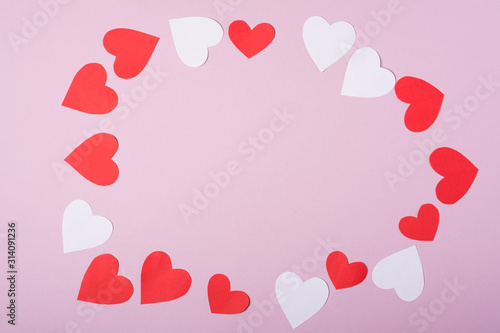 Red and white handmade paper hearts valentines frame on pink background, copy space, top view
