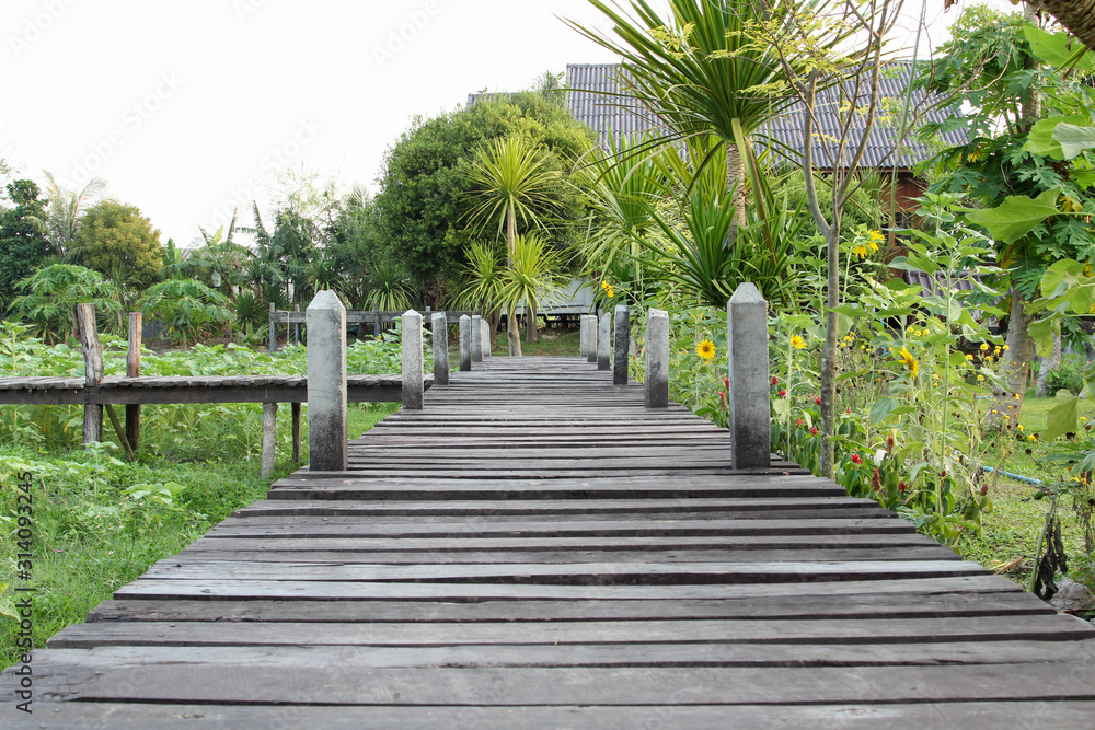 Fototapeta premium Old wooden bridge on green grass lawn.