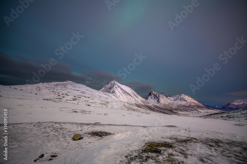 Dramatic night with many clouds and stars on the sky over the mountains in the North of Europe - Tromso, Norway.long shutter speed.