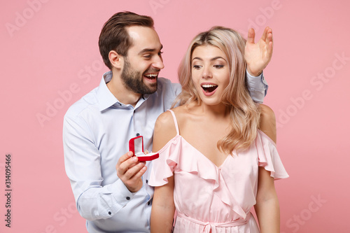 Obraz na płótnie Excited young couple two guy girl in party outfit celebrating posing isolated on pastel pink wall background