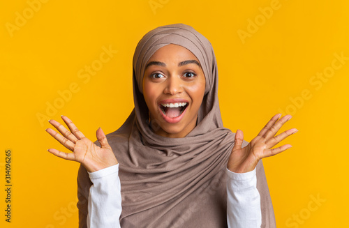 Portrait of excited black muslim girl in headscarf exclaiming in amazement