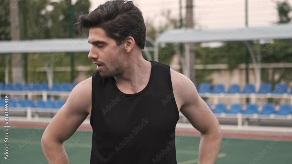 Concentrated handsome man stretching his neck with closed eyes on stadium outdoors Concentrated handsome man stretching his neck with closed eyes on stadium outdoors