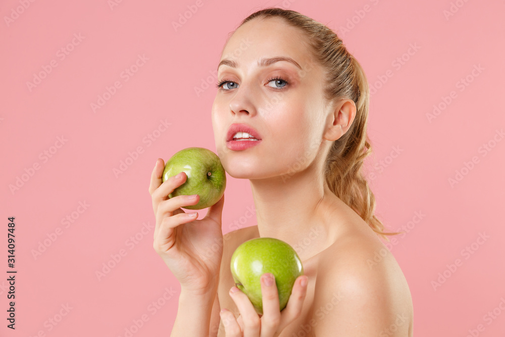Close up blonde half naked woman 20s perfect skin nude make up hold apple isolated on pastel pink wall background studio portrait. Skin care healthcare cosmetic procedures concept. Mock up copy space. Close up blonde half naked woman 20s perfect skin nude make up hold apple isolated on pastel pink wall background studio portrait. Skin care healthcare cosmetic procedures concept. Mock up copy space.