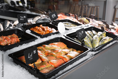 Different types of marinated fish on ice in supermarket