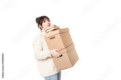 Brunette woman holding two heavy cardboards with books on top of them. Moving concept.