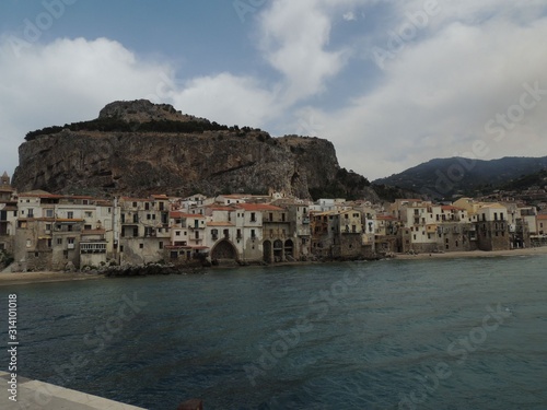 Cefalù – Panorama of the ancient port with the sandy beach and in the background old buildings and green hills