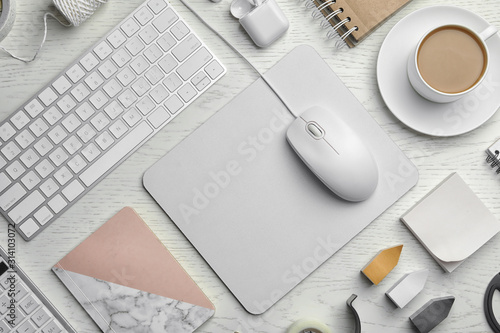Flat lay composition with wired computer mouse, keyboard and stationery on white wooden table